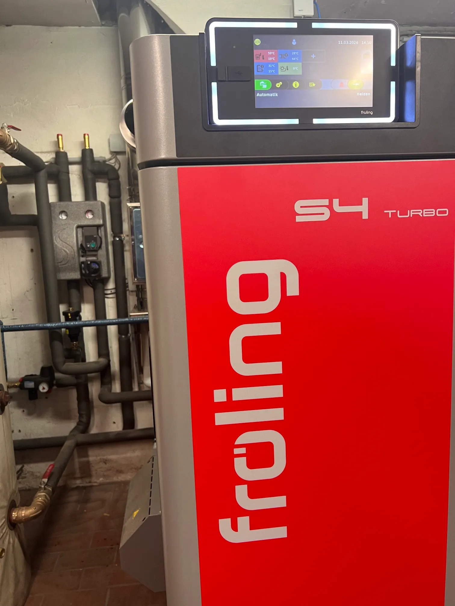 Installierter Fröling Holzheizkessel mit Touch-Bedien­display in einem Heizungs­raum