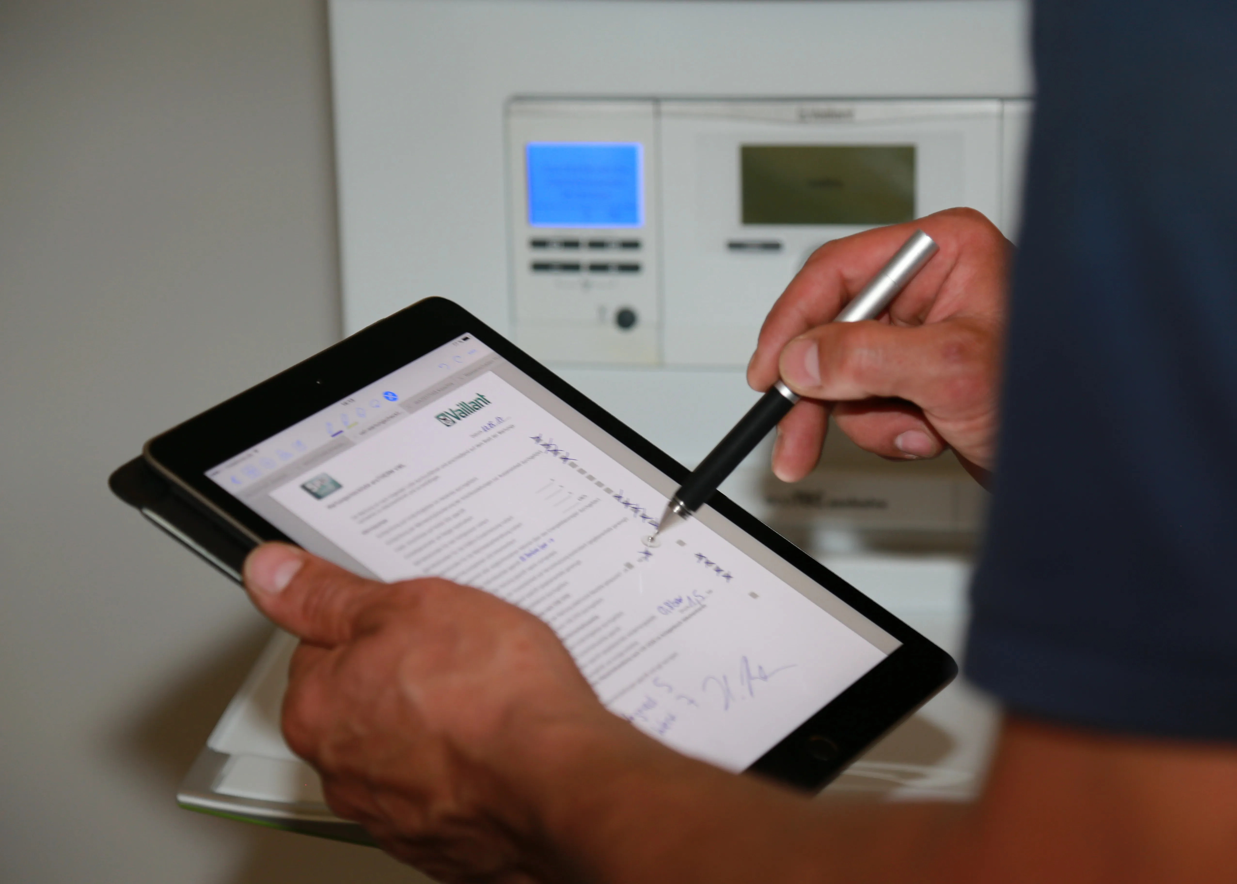 Techniker dokumentiert eine Heizungs­wartung digital auf dem Tablet direkt am Gerät